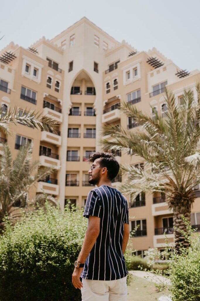 A Man In Striped Blue Shirt Standing Beside Green Trees